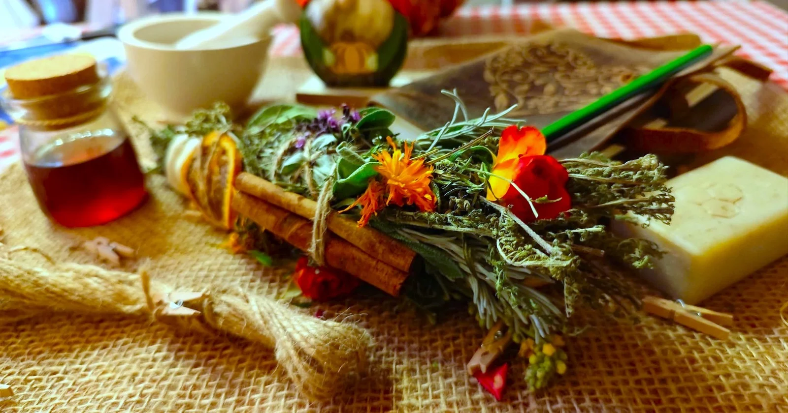 Räucherbündel aus Kräutern, Blüten und Zimtstangen, daneben Tinktur und Seife